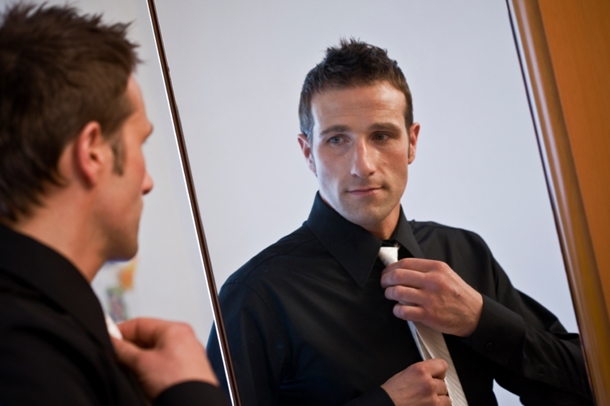 Man Putting on Tie in front of Mirror